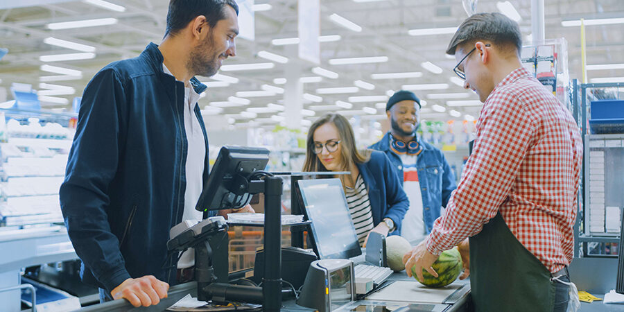At the Supermarket: Checkout Counter Professional Cashier Scans Groceries and Food Items. Clean Modern Shopping Mall.